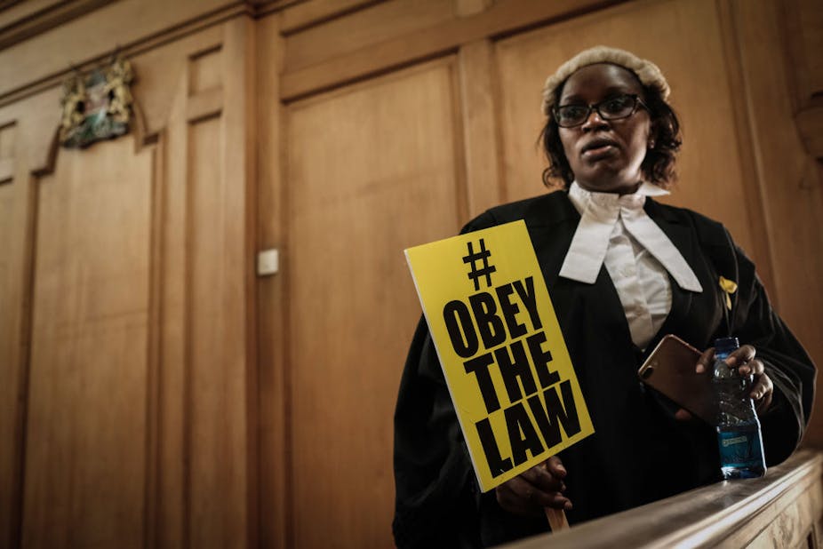 A woman lawyer holds a placard with the word "Obey the law"