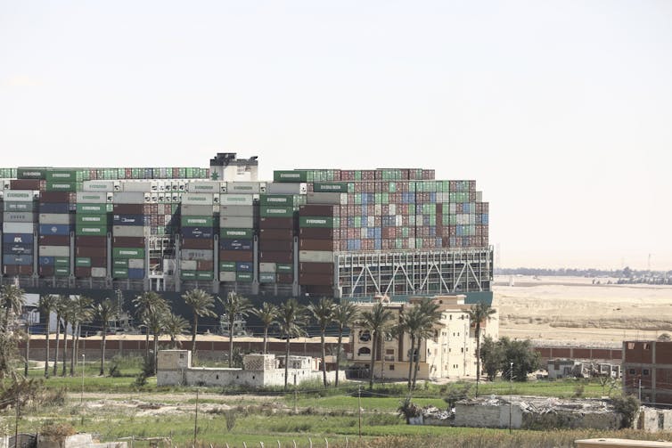 The Ever Given cargo ship loaded with shipping containers appear stuck in the mud along the Suez Canal in March 2021