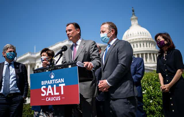 Thomas Suozzi and several other lawmakers stand in front of a podium that says 'bipartisan salt caucus' during a press conference with the Capitol in the background on April 15, 2021