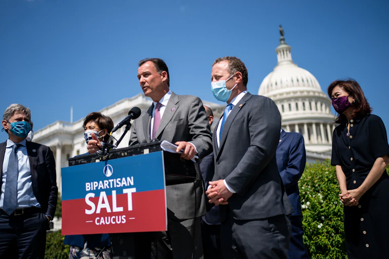 Thomas Suozzi and several other lawmakers stand in front of a podium that says 'bipartisan salt caucus' during a press conference with the Capitol in the background on April 15, 2021