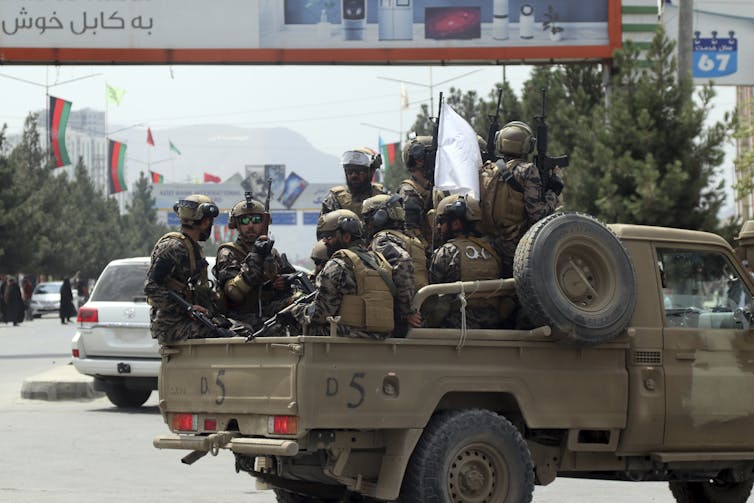 A truck of soldiers drives down a street