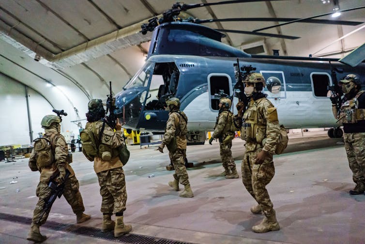 Soldiers stand near a helicopter