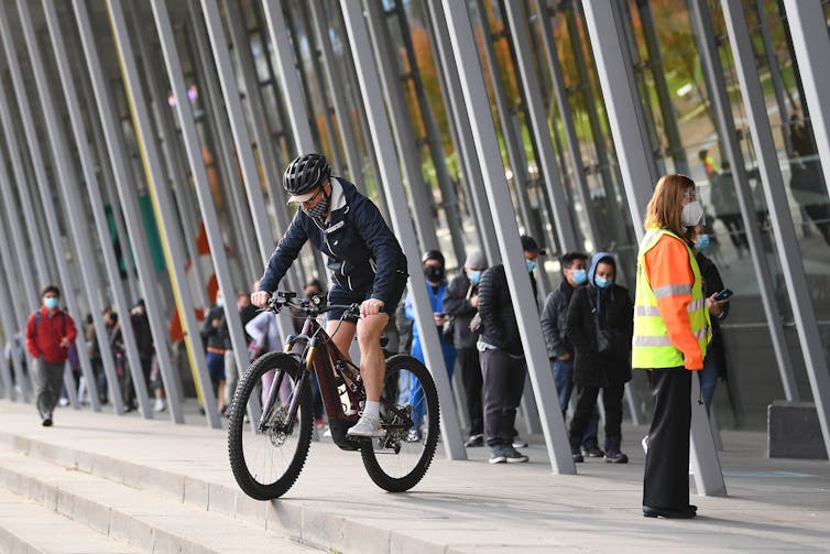 man on bike near long queue of people