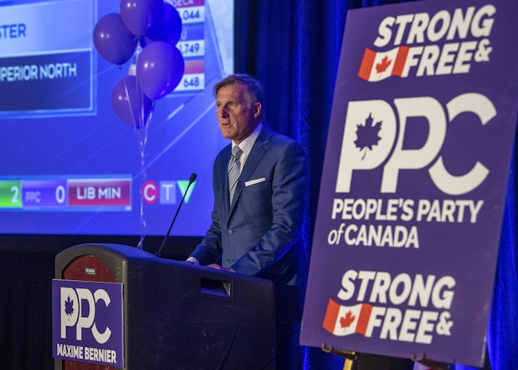 Bernier speaks from a podium with a party banner in the foreground