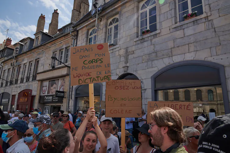 Manifestantes brandissant des pancartes contre la vaccin lors d’une manifestation à Besançon le 14 août 2021