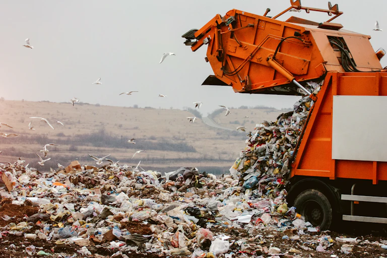 A rubbish truck dumping waste in a landfill site.