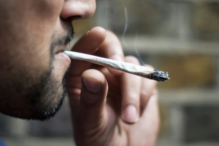 Close-up photo of a man smoking a cannabis joint