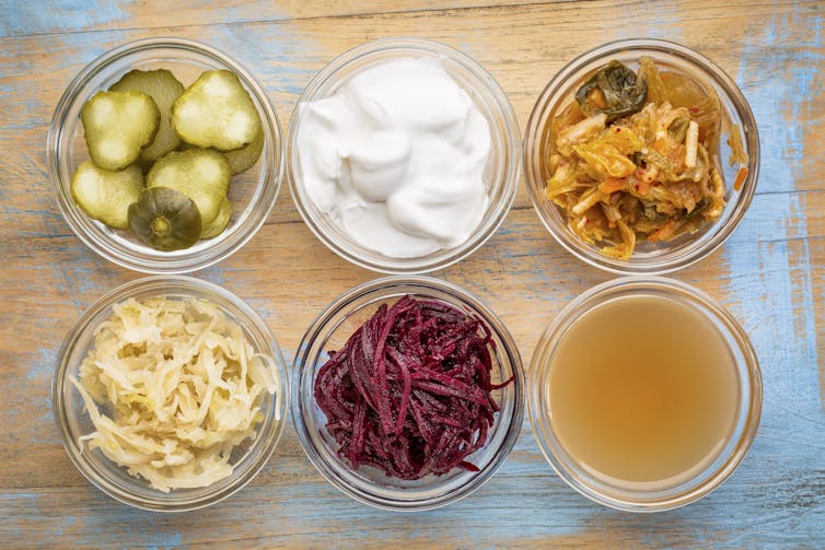 Small glass pots filled with different probiotic foods, such as yoghurt and sauerkraut.