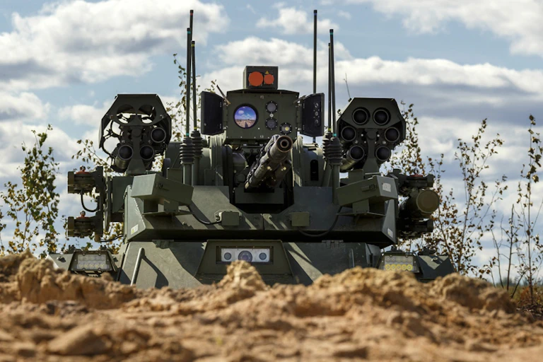 Tank bardé de canons apparait derrière une butte de terre.