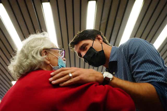 Trudeau in a mask talks to an elderly woman in a mask in a subway station.
