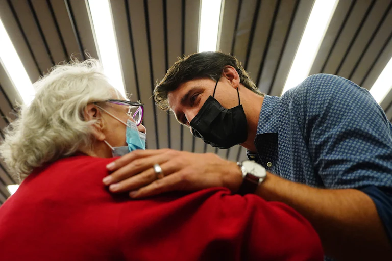 Trudeau in a mask talks to an elderly woman in a mask in a subway station.