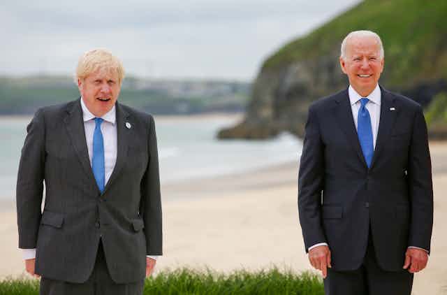 Prime minister Boris Johnson and US President Joe Biden, both in dark suits and blue ties, standing socially distanced in the G7 summit group photo