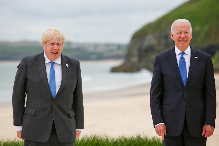 Prime minister Boris Johnson and US President Joe Biden, both in dark suits and blue ties, standing socially distanced in the G7 summit group photo