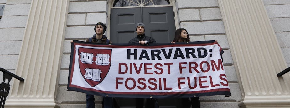 Protesters hold up a banner telling Harvard to divest from fossil fuels.