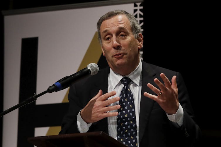 Harvard University President Larry Bacow speaking before a microphone