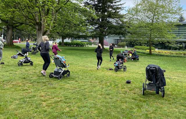 A group of women with infants in strollers exercising in a park