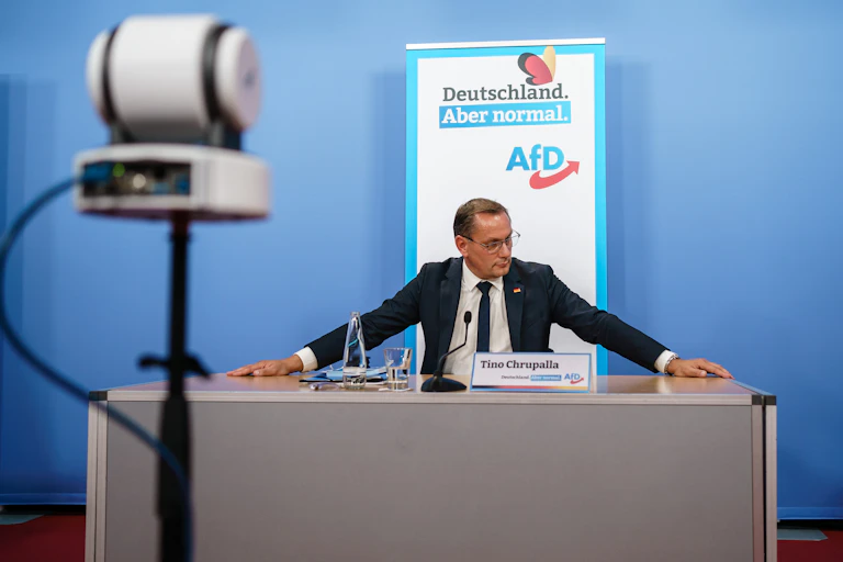 Tino Chrupalla sitting at a desk preparing for a press conference.