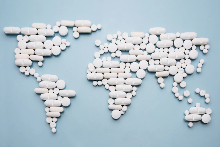 Pills laid out on blue background in shape of world map