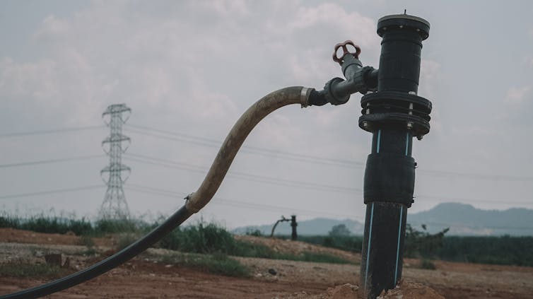 A metal pipe with a plastic tube extending towards the ground.