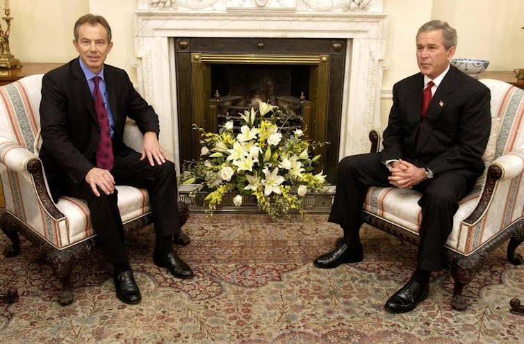 A 2003 photo of Tony Blair and George W Bush sitting in armchairs in front of a fireplace during a meeting at Downing Street.