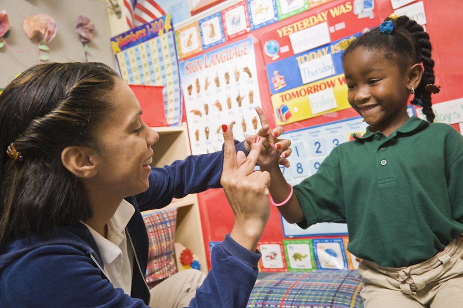A teacher shows pre-school girl sign language.