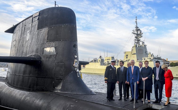 President Emmanuel Macron (2/L) and Australian Prime Minister Malcolm Turnbull (C) standing on the deck of HMAS Waller, a Collins-class submarine operated by the Royal Australian Navy.