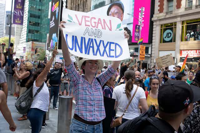 A woman protesting the COVID-19 vaccine holds a poster that says "Vegan and Unvaxxed" in the midst of a protest march held in New York on Sept. 18, 2021.