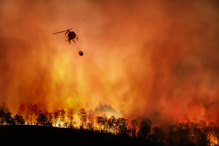 Helicopter with water over a fire.