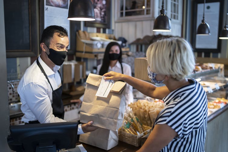 restaurant employee hands bag of takeout to customer at counter