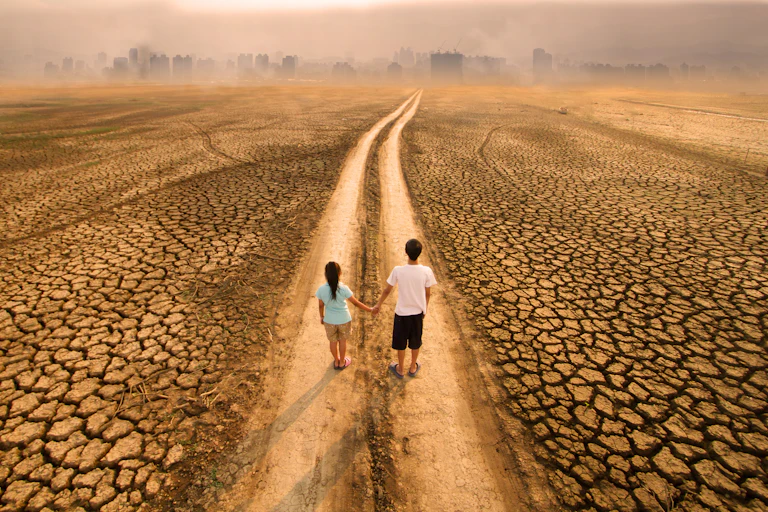 two people standing in a lane in a parched landscape, a city skyline in the distance