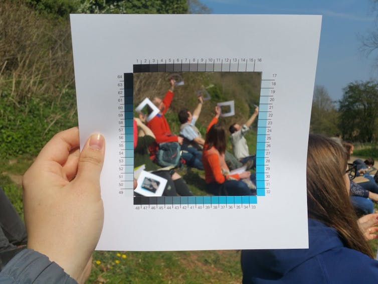 a sqaure picture of people holding up the cyanometre surrounded by 53 squares in different shades of blue.
