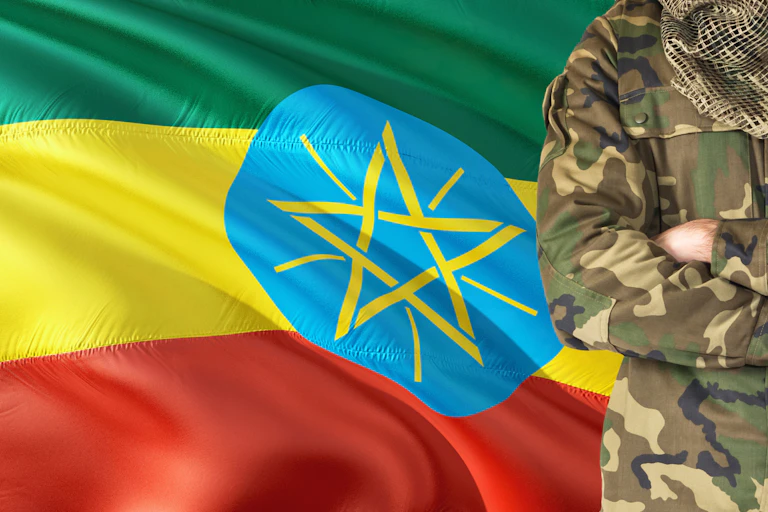 Ethiopian soldier with national waving flag on background