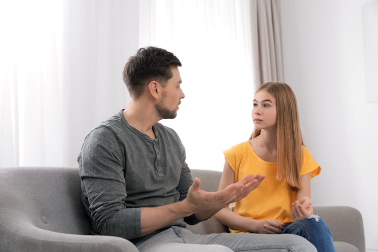 Father talking to daughter on the couch.