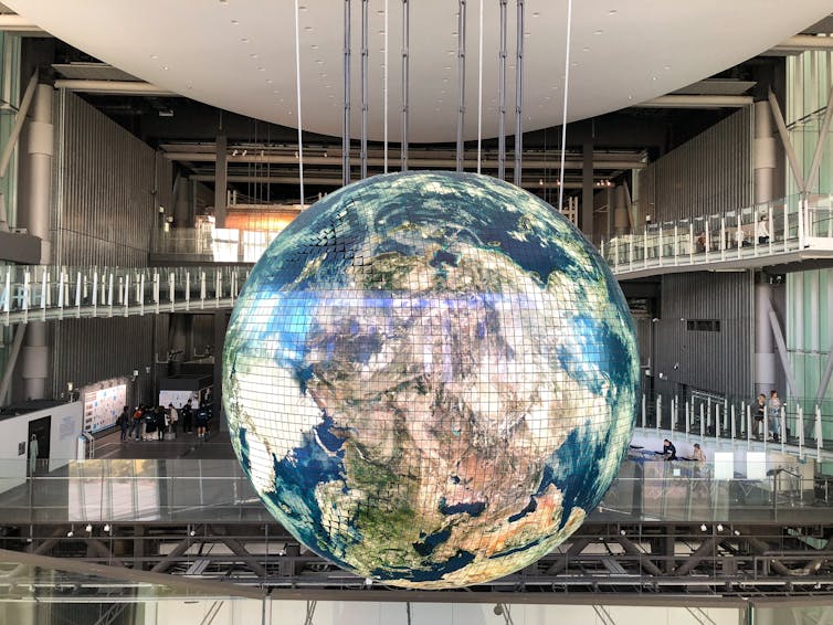 Giant Earth globe hangs in modern building.