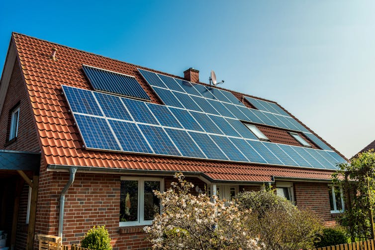 A house with a red tile roof covered in solar panels.