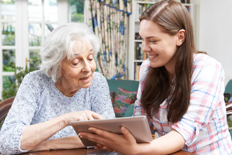 Grandmother looks at ipad with her granddaughter