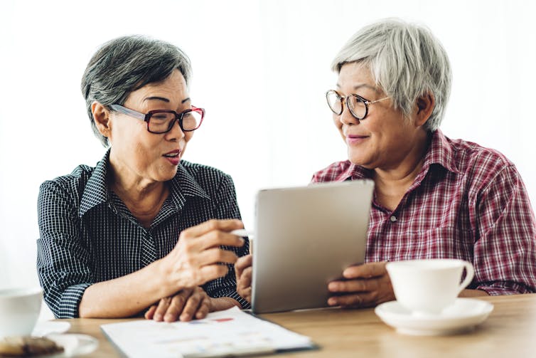 Two older women look at an iPad together