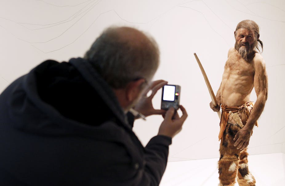 A man takes pictures of a statue representing an iceman named Otzi, discovered in 1991 in the Italian Alps.