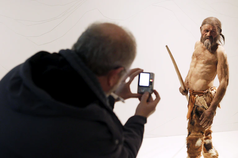A man takes pictures of a statue representing an iceman named Otzi, discovered in 1991 in the Italian Alps.