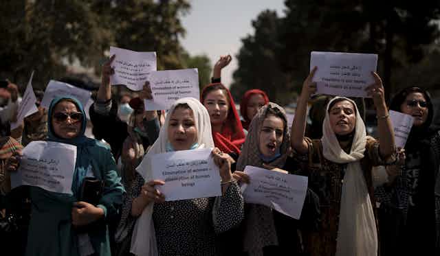 Afghan women carry signs demanding rights.