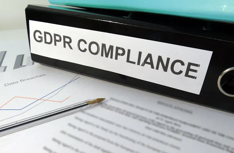 Artificial intelligence: Folder labeled GDPR COMPLIANCE on cluttered desk.