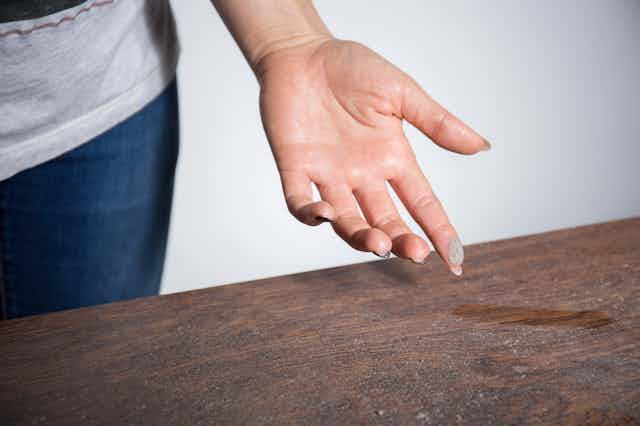 A person wipes dust from a wooden surface.