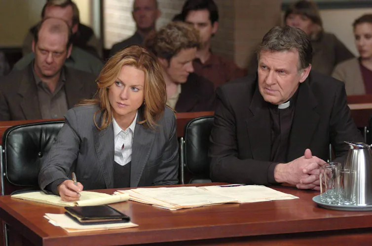 Laura Linney as a lawyer and Tom Wilkinson as a priest sit at a courtroom table in a scene from the film The Exorcism of Emily Rose.
