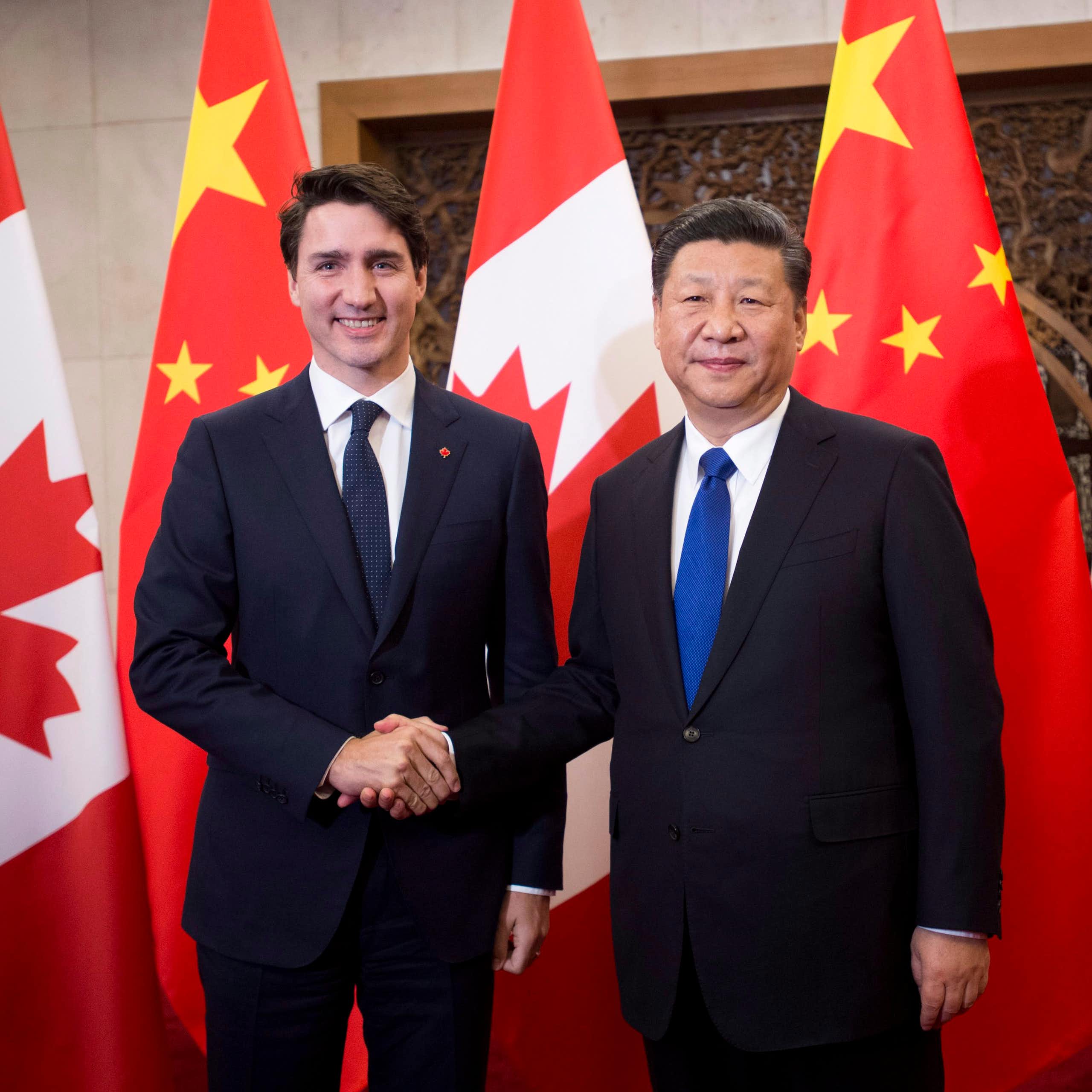 Justin Trudeau serre la main de  Xi Jinping devant des drapeaux canadiens et chinois