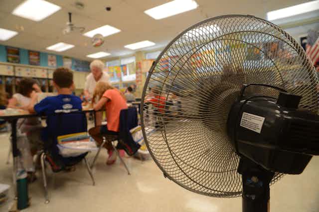 Standing fan blows on students in elementary school classroom
