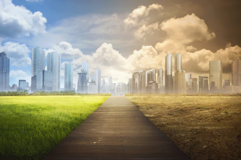 A wooden path with a green city on the left and a barren city on the right