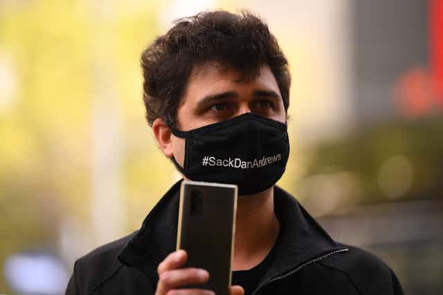Protester in Melbourne wearing a mask saying #SackDanAndrews