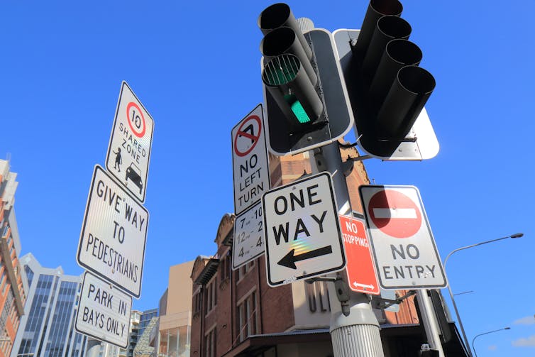 Traffic lights with road signs around them in Sydney.