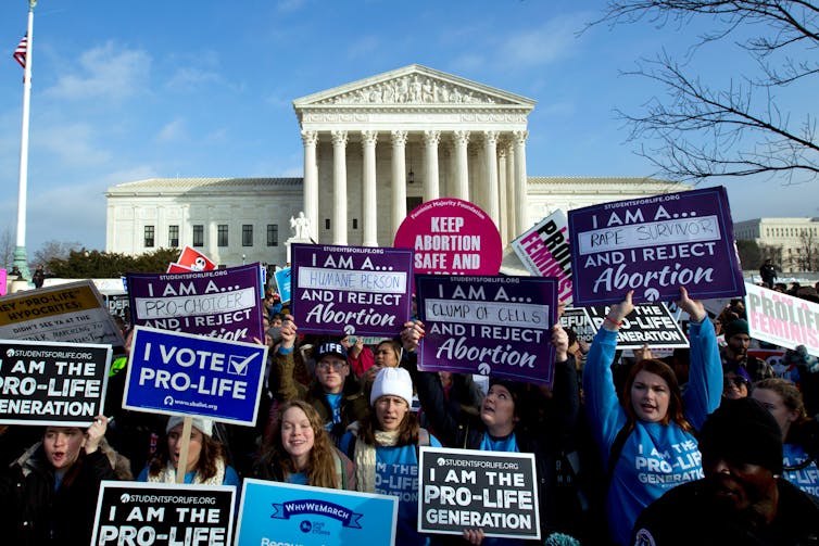 Anti-abortion activists holding signs in front of the Supreme Court.