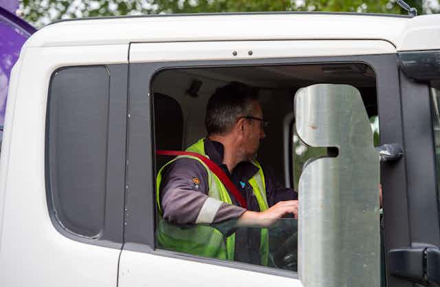 An HGV driver operating a lorry and looking away from the camera
